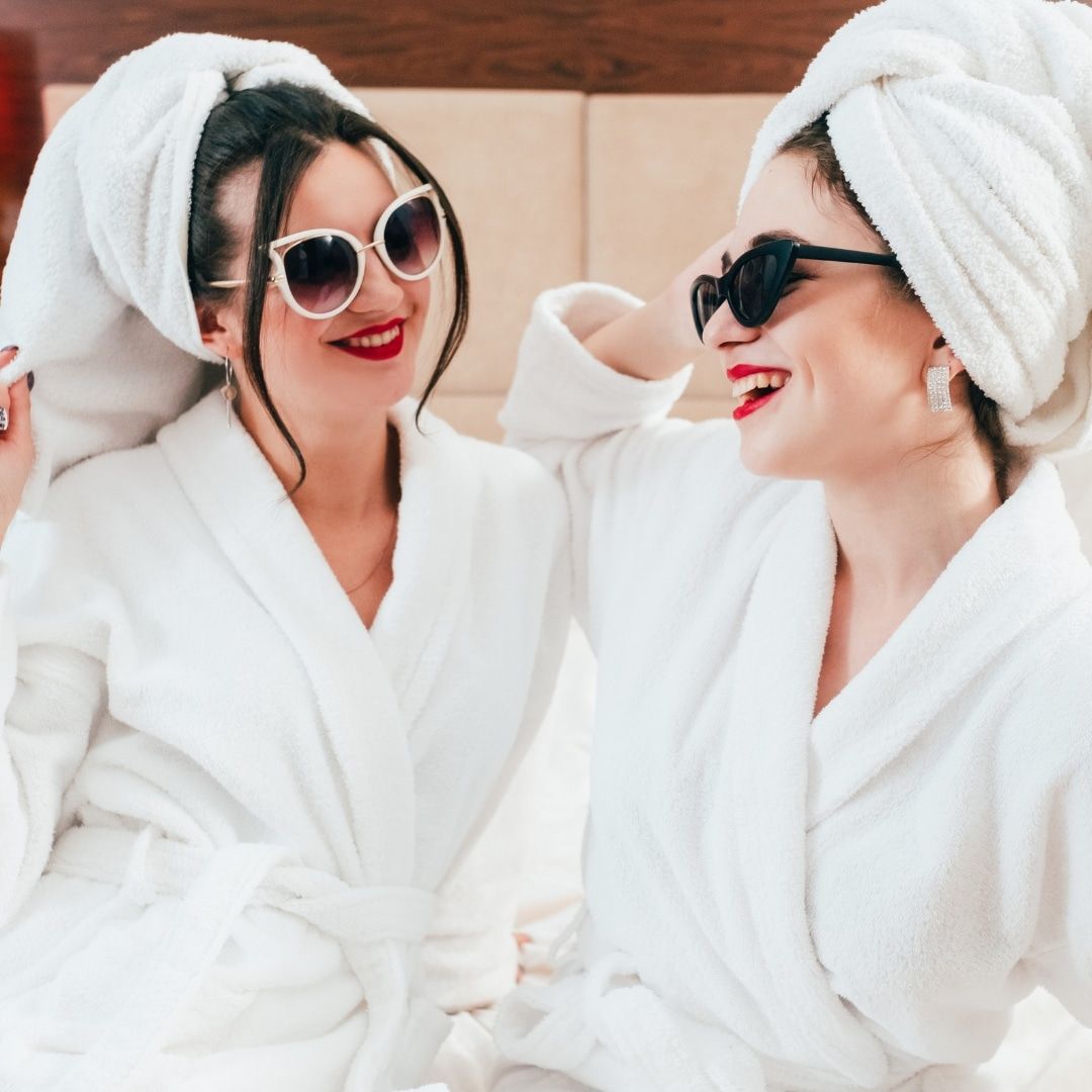 Two friends in white robes and towel turbans laughing together