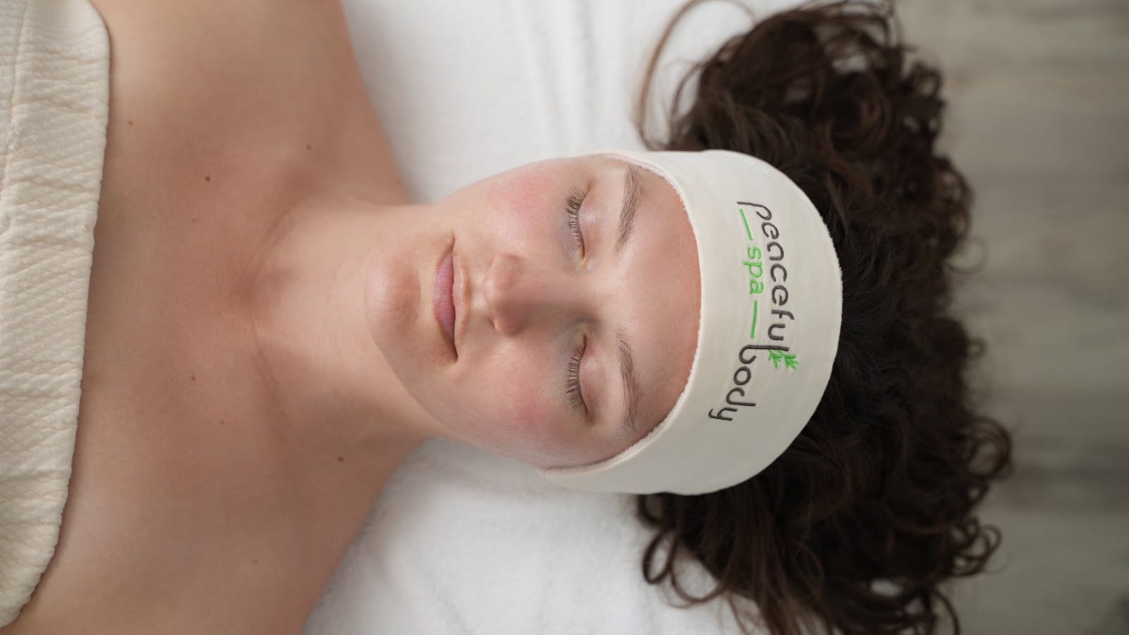 A client mid-facial, headband on, eyes closed